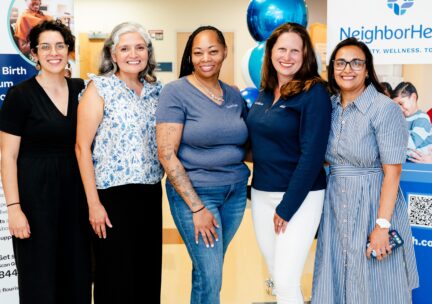 Leaders from NeighborHealth Ob/Gyn and Flourish Care pose in front of banners