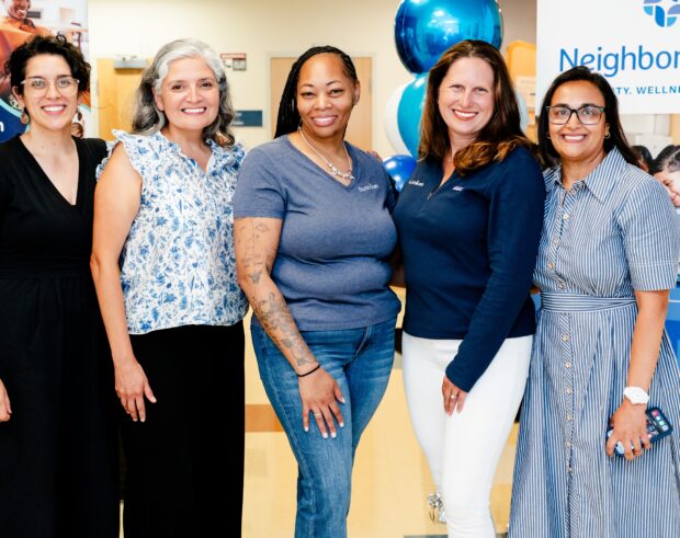 Leaders from NeighborHealth Ob/Gyn and Flourish Care pose in front of banners